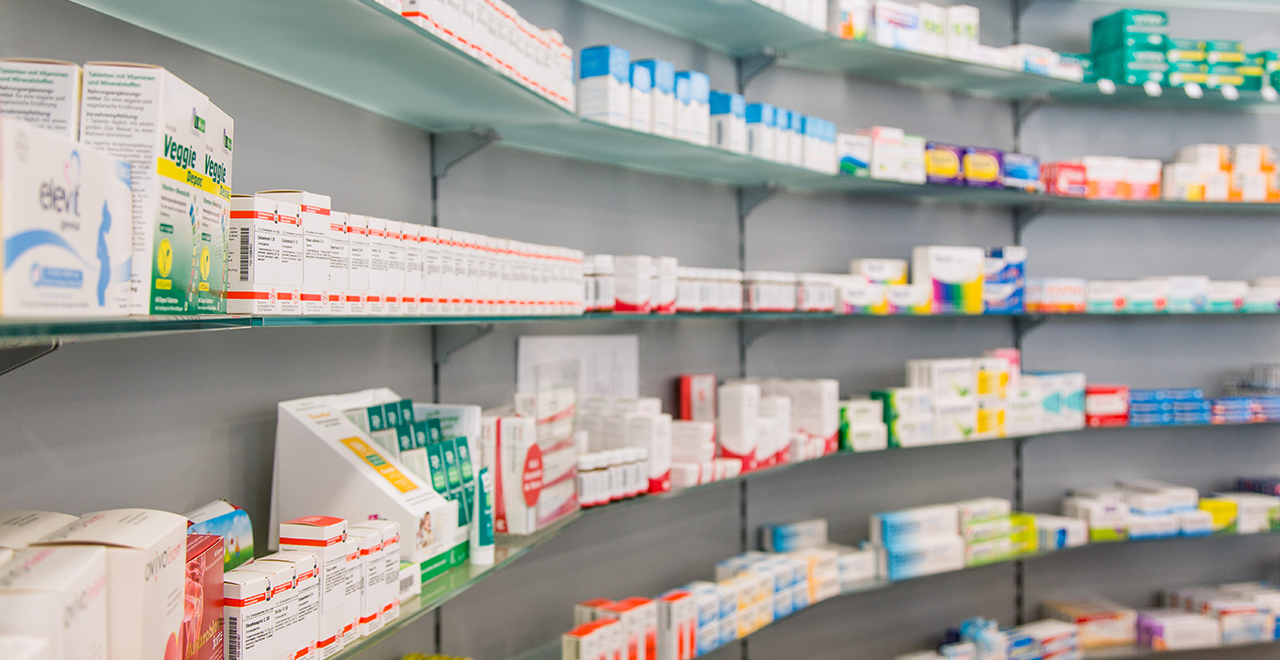 Regale in einer Apotheke mit verschiedenen Medikamenten und Pflegeprodukten. Die Regale sind gut organisiert, und das Bild zeigt eine Vielzahl von Verpackungen und Marken.