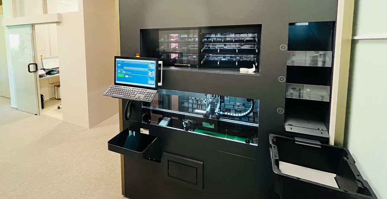 Großes automatisiertes Apotheken-Lagersystem im Verkaufsbereich mit geschlossener Front und seitlichem Bedienplatz.