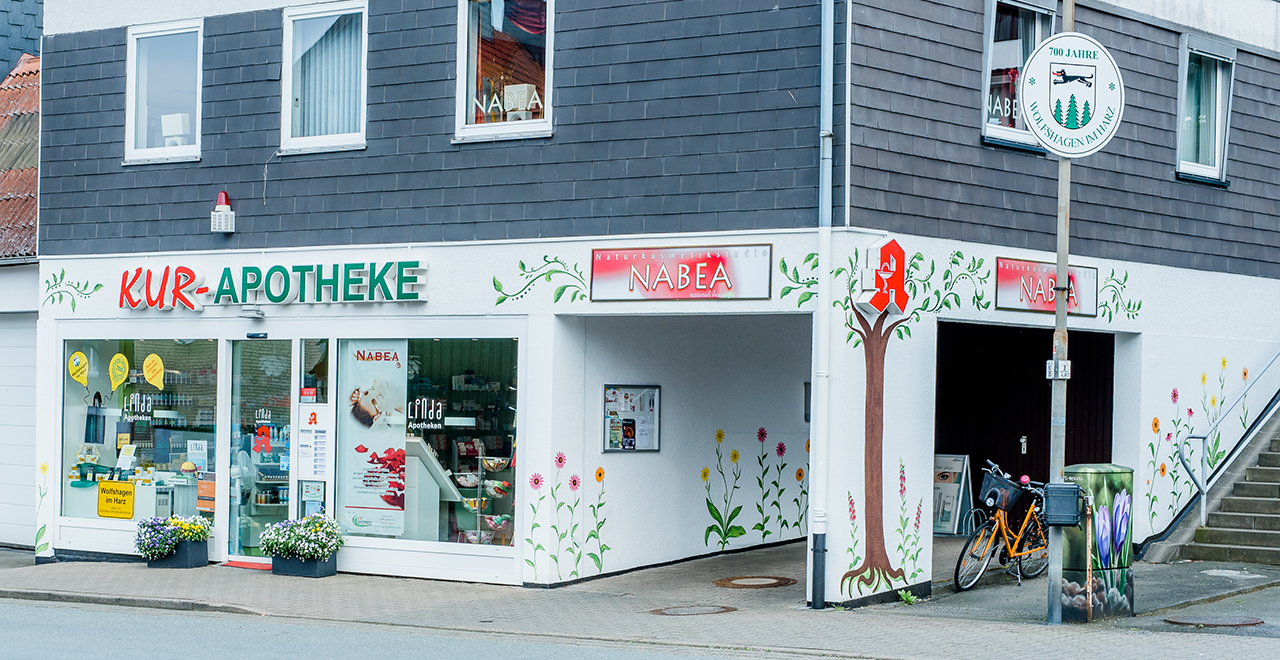 Kur-Apotheke mit bunt bemalter Fassade, Schaufenstern und einem Fahrrad vor dem Eingang.
