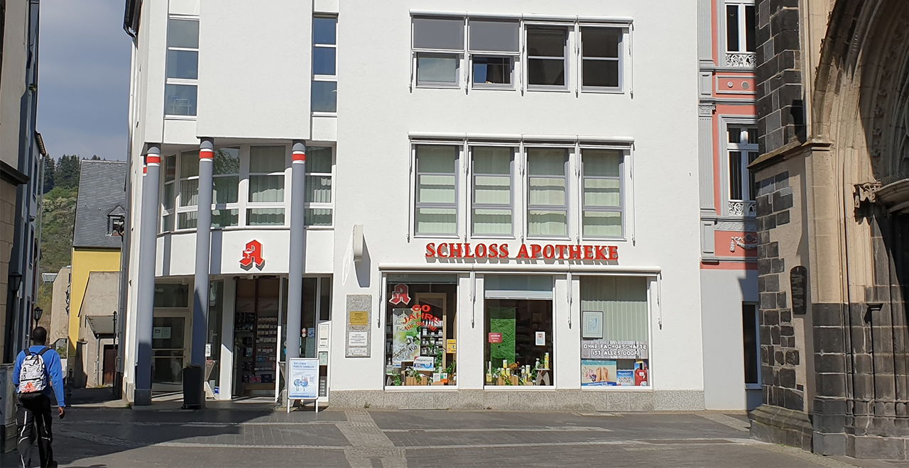 
Moderne Schloss Apotheke in einem weißen Gebäude in der Altstadt, mit großen Schaufenstern und Apotheken-Logo.
