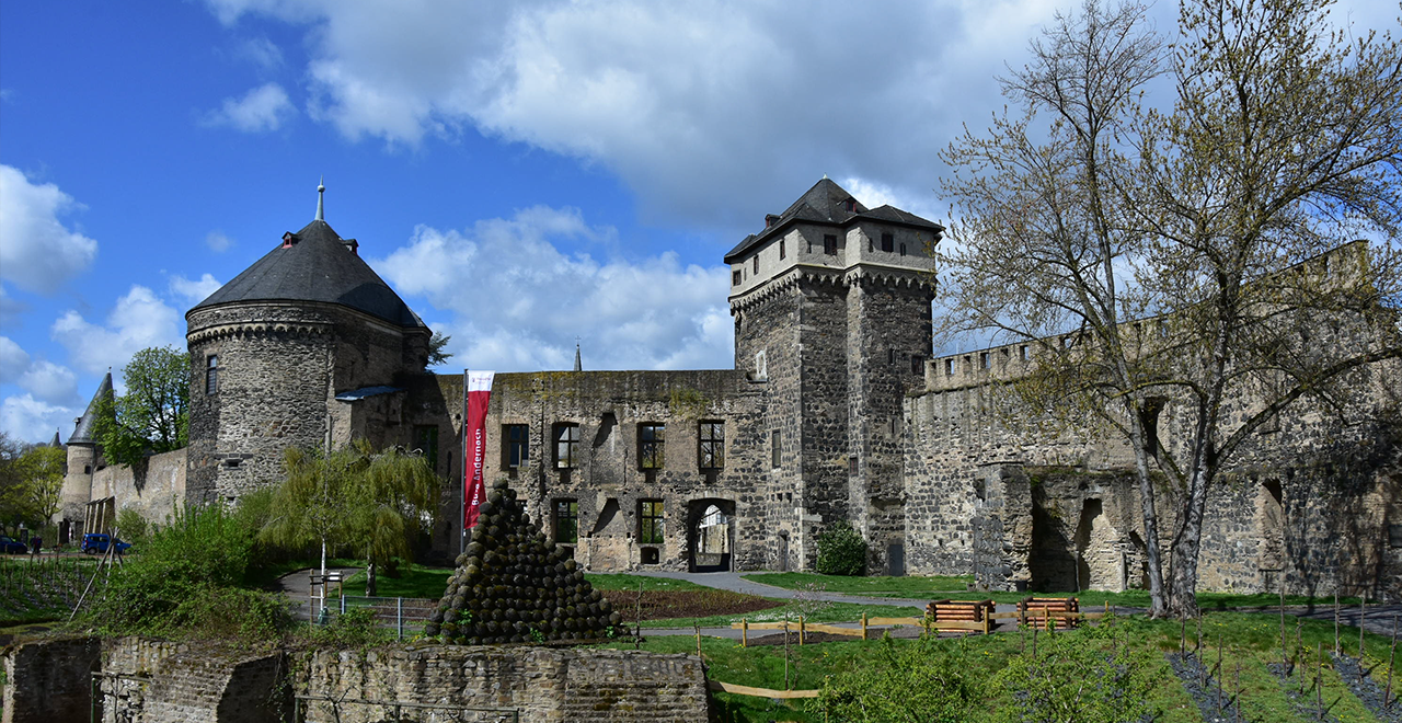 Mittelalterliche Burganlage mit Rund- und Ecktürmen in Andernach bei sonnigem Wetter.
