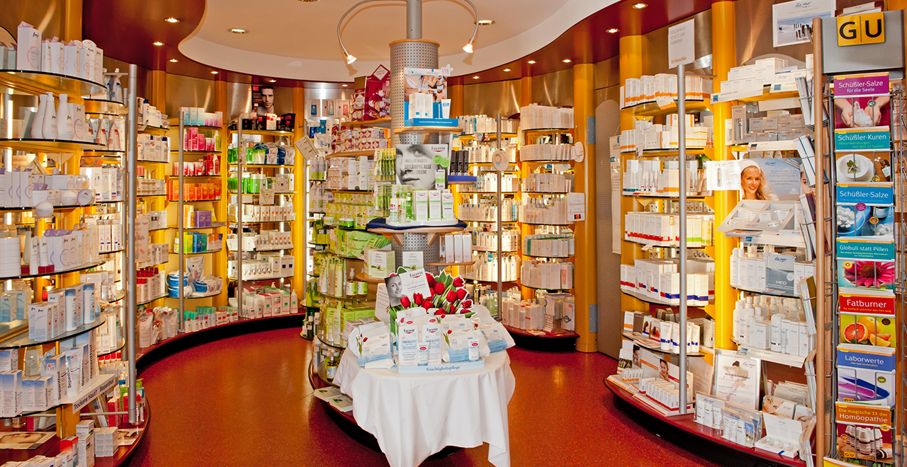Innenansicht der St. Alto Apotheke mit stilvoller Präsentation von Kosmetik- und Pflegeprodukten in hell beleuchteten Regalen.